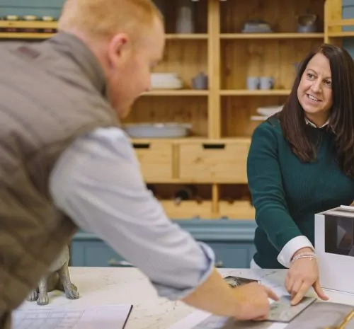 Woman showing a customer some plans for a new kitchen